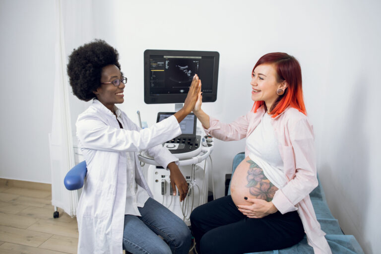 Pregnant woman and healthcare professional celebrating with high-five and ultrasound scan