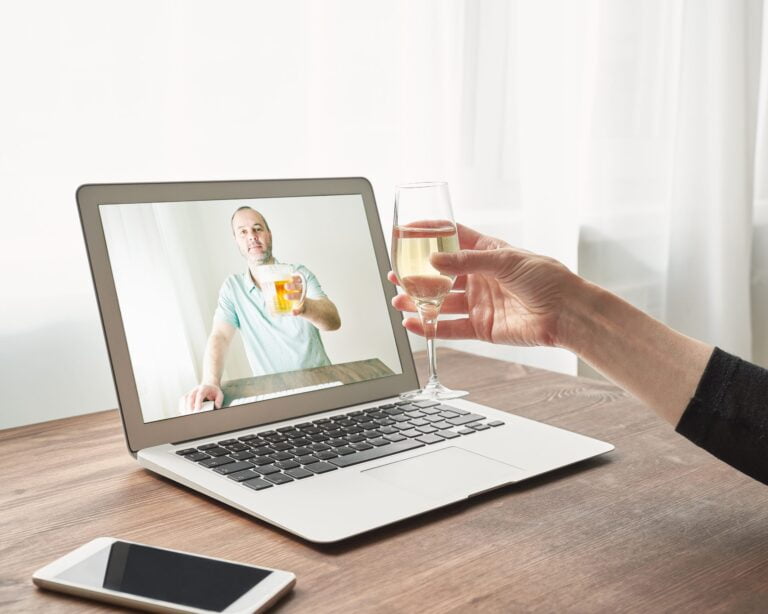 Online dating connection on laptop screen and glass of wine