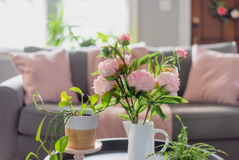 Living room decor with pink pillows and peonies in a vase, home design inspiration.