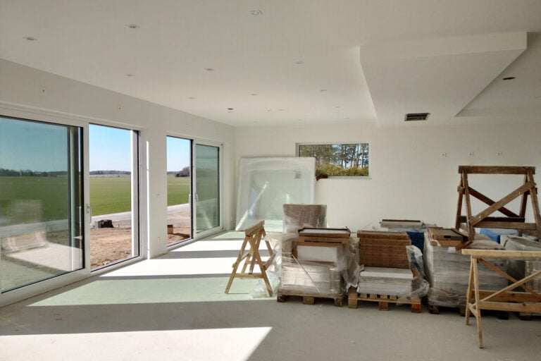 Interior of a house under renovation with large windows and construction materials.